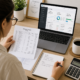 A clean, modern flat-lay photo of a small business owner reviewing financial ledgers and a laptop showing bookkeeping software at a desk